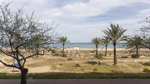 A beach with palm trees, a pathway, and a view of the sea. - Luxury vacations in Bermuda Apartments in front of the beach - ONLY FAMILIES (Playa de Gandía)