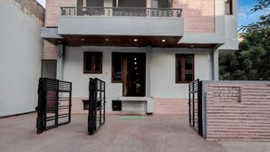 Una casa moderna de dos pisos con balcón, entrada portón y un pequeño porche.