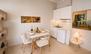 Eine kompakte Küche mit weißen Schränken, einem Esstisch mit Stühlen und einer kleinen Kücheninsel mit Lampe.