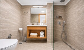 Ein modernes Badezimmer mit Toilette, Waschbecken, Spiegel, Handtuchhalter und Dusche.