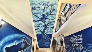 En trappe med et mural af et træ og en hval, der fører op til et værelse med et skilt for bed and breakfast.