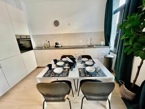 A modern kitchen with white cabinets, a dining table set with plates, cups, and a menu. - Antwerp Sanctuary Near Old Town (Antwerp)