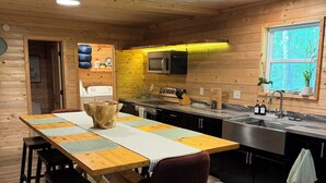 En inredning med träpanel, ett köksområde, ett matbord med stolar och ett fönster med utsikt.