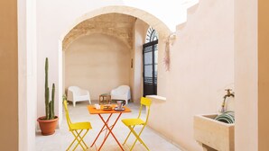 Un patio al aire libre con una mesa, sillas, un cactus en maceta y una fuente.
