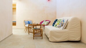 Una sala de estar acogedora con un sofá, dos sillones, una mesita y una lámpara de pared.