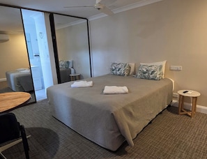A hotel room with a bed, a small round table, a chair, and a mirror. - Sisleys Motel (Lismore)