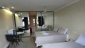 A hotel room with two beds, a desk with a computer, a chair, and a large mirror. - Sisleys Motel (Lismore)