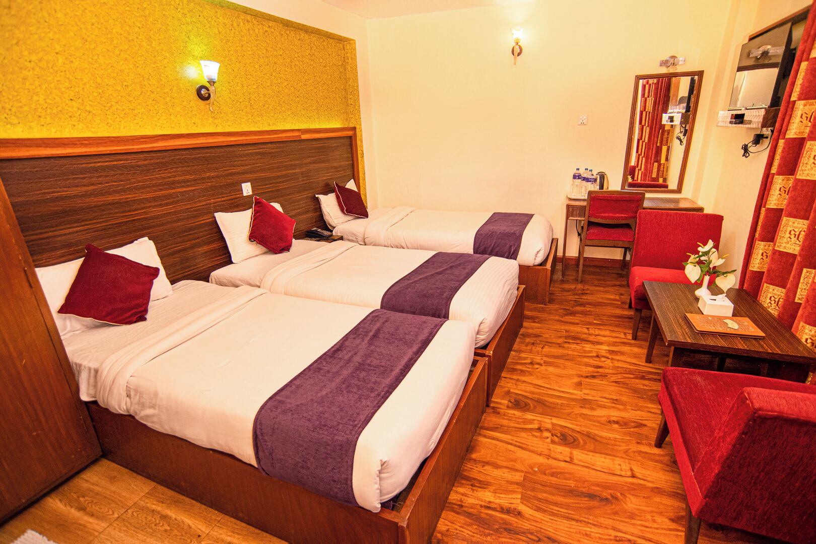 A hotel room with two beds, a small table, and a chair.