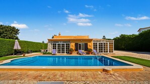 Una piscina con sillas de descanso, un patio y un edificio con amplias ventanas.