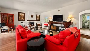 Una sala de estar con sofás rojos, televisor, chimenea y decoración tradicional.