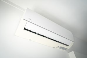 Eine weiße Wand-Klimaanlage mit Bedienfeld und Aufkleber.