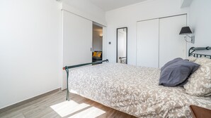 A bedroom with a bed, a mirror, a lamp, and a door leading to another room. - Holiday Home 'Belavista - By Staywise' with Sea View, Wi-Fi and Air Conditioning (Portimão)