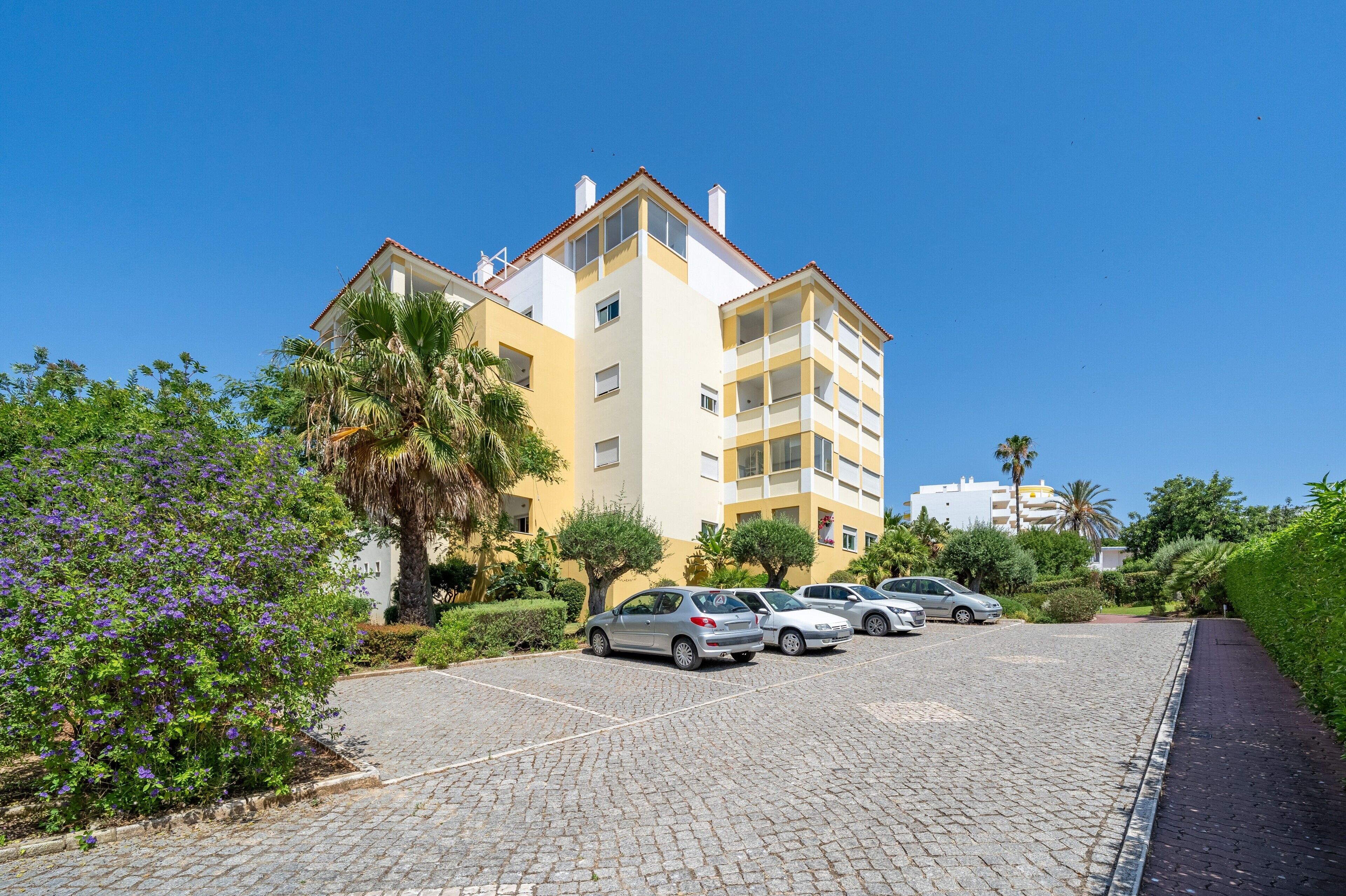 A multi-story residential building with a parking area in front.