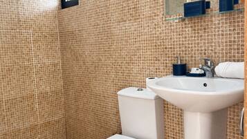 Un baño con inodoro, lavabo y paredes con azulejos.