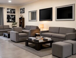 A modern living room with a sofa set, a coffee table with books, and a lamp.