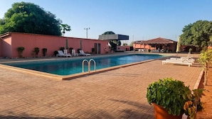 A swimming pool with lounge chairs, a covered area, and a brick patio. - Viana Hotel (Viana)