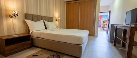 Un dormitorio con cama, mesitas de noche, televisión y armario.