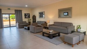 A hotel lobby with a sofa set, a coffee table, a TV, and a plant. - Viana Hotel (Viana)