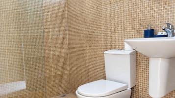 Ein Badezimmer mit Toilette, Waschbecken und Duschbereich.