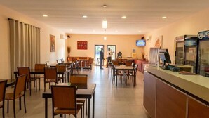 A restaurant with tables and chairs, a counter, and a television screen. - Viana Hotel (Viana)