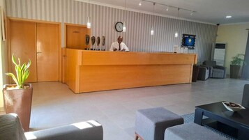 A reception desk with a clock, a television, and a plant.