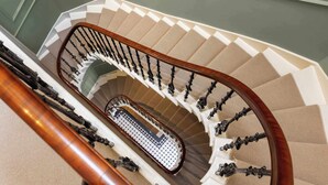 A spiral staircase with a wooden handrail and a patterned carpet. - Stuart Suite (Edinburgh)