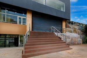A modern building with a set of stairs leading to a door, a stone wall, and a clear sky. - Deluxehotel Chakripuram (Hyderabad)