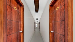 A hallway with wooden doors labeled 204 and 205, leading to a bright room. - Deluxehotel Chakripuram (Hyderabad)