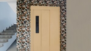 A beige door with a stone wall, a metal gate, and a staircase. - Deluxehotel Chakripuram (Hyderabad)