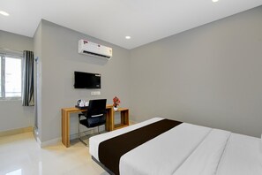 Ein Hotelzimmer mit einem Bett, einem Schreibtisch mit Stuhl, einem Fernseher und einer Klimaanlage.