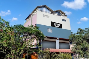 Un hotel de varios pisos con un llamativo letrero que dice 'HOTEL', ventanas amplias y un toldo rojo.