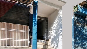 Ein Gebäudeeingang mit einem Metallgitter, einer blauen Säule und einer gefliesten Eingangshalle.