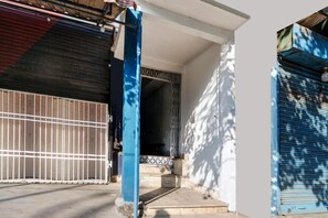 A building entrance with a metal gate, a blue pillar, and a tiled entrance. - Deluxe Noonmati Guwahati Hotel Sundari (Guwahati)