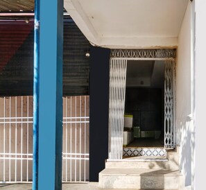 A residential entrance with a metal gate, a tiled entrance, and a staircase leading to a dark interior. - Deluxe Noonmati Guwahati Hotel Sundari (Guwahati)