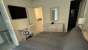 Un dormitorio con una cama grande, un aparador, un espejo, un televisor y un vestidor.
