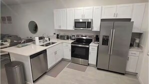 Una cocina moderna con armarios blancos, electrodomésticos de acero inoxidable y lavavajillas.