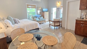 A bedroom with a bed, a chair, a table, and a TV. - Indigo @Serendip Vacation Condos (Cruz Bay)