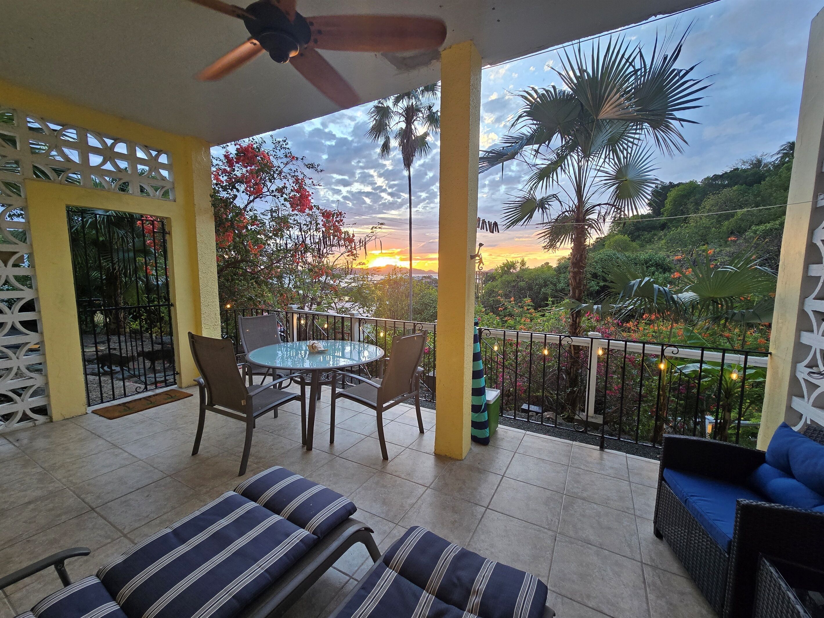 A balcony with a table and chairs, a sofa, and a ceiling fan.
