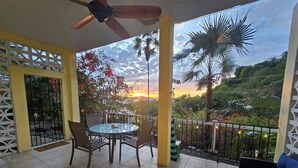 A balcony with a table and chairs, a sofa, and a ceiling fan. - Indigo @Serendip Vacation Condos (Cruz Bay)