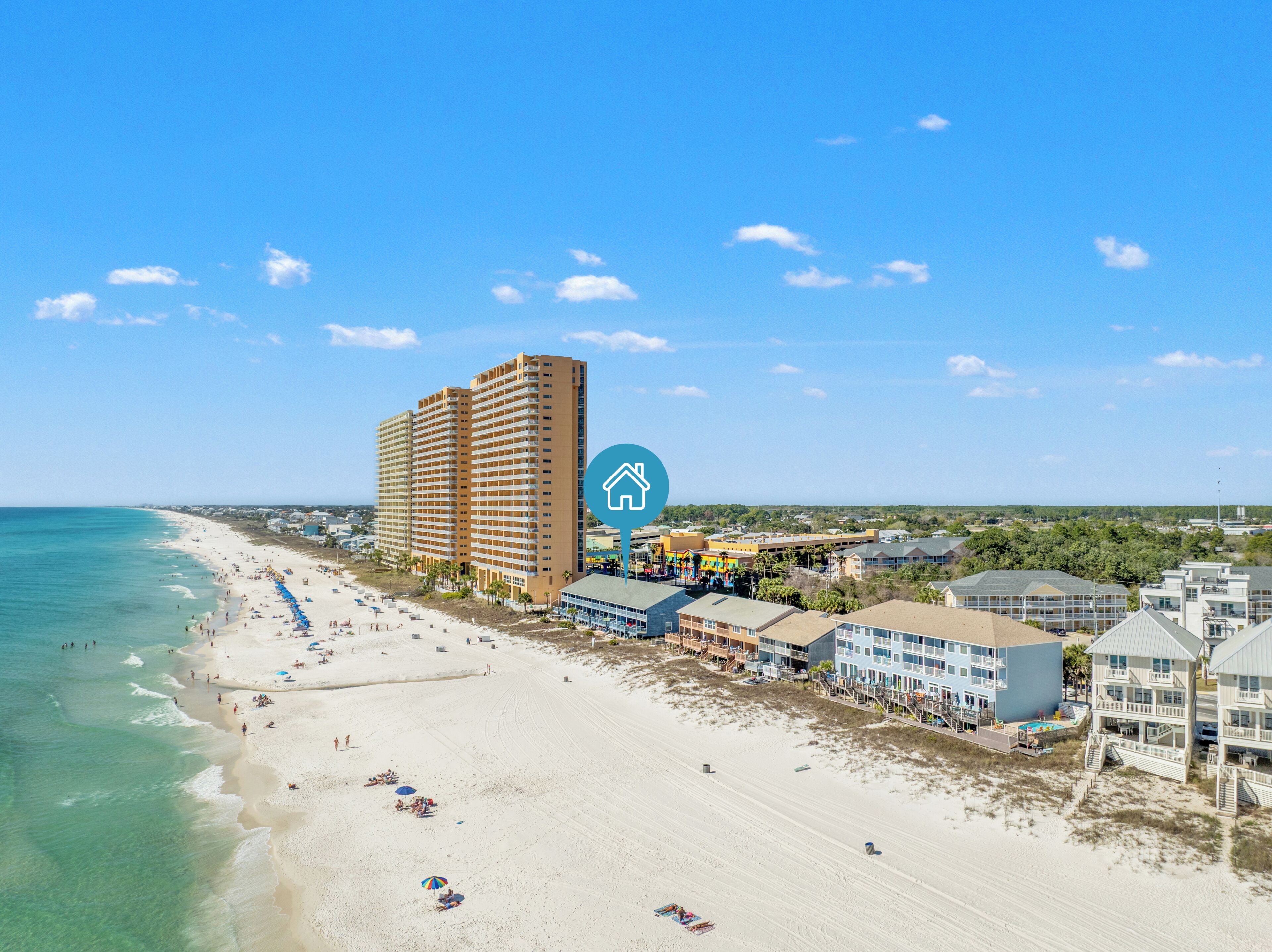 A beachfront hotel with multiple buildings, a sandy beach, and a clear blue sky.