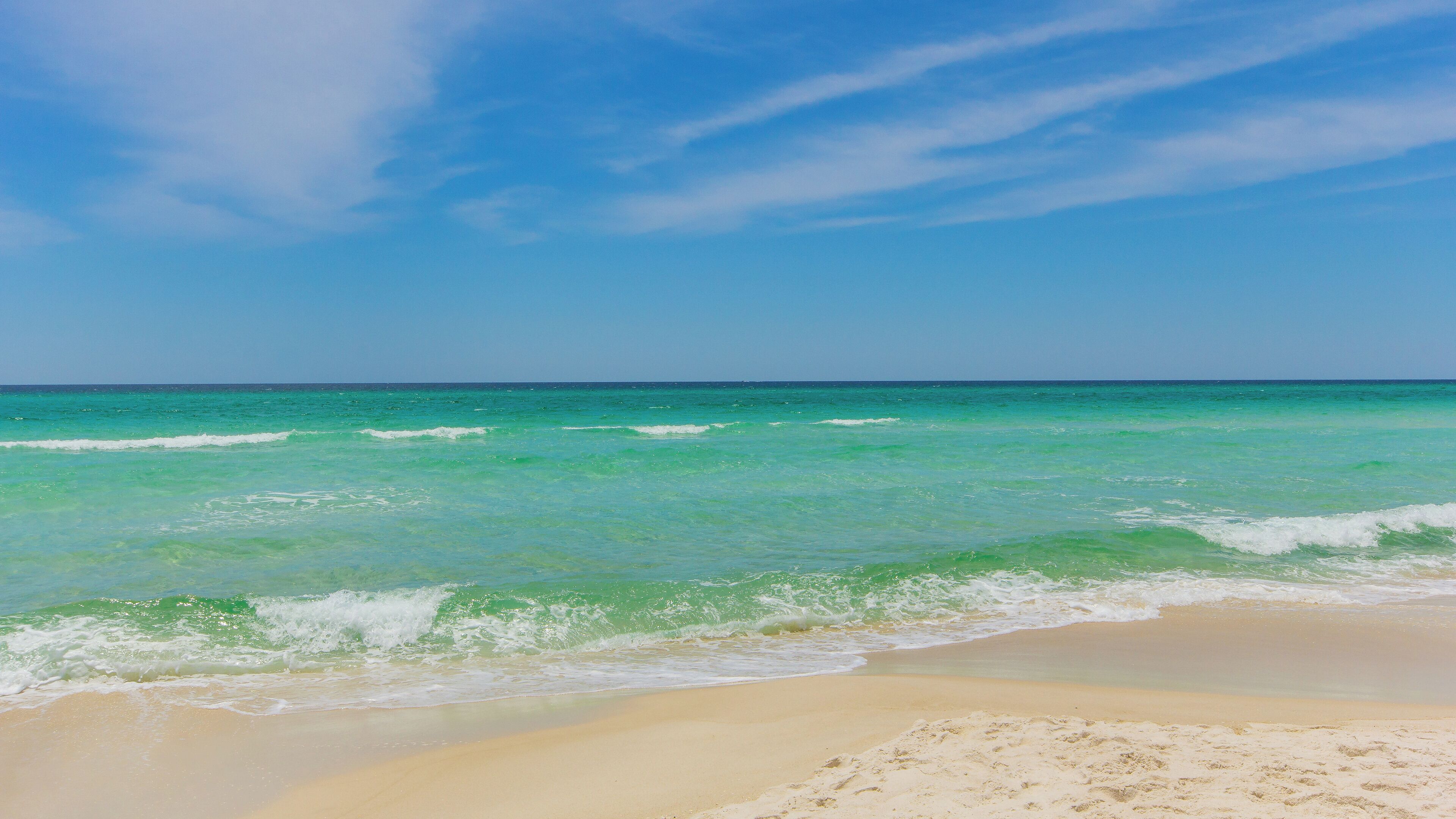 A beach with clear turquoise water and a sandy shore.
