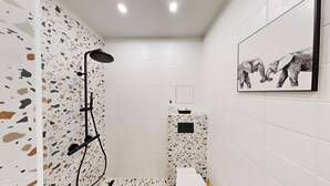 Casa de banho moderna com chuveiro, lavatório e uma imagem de elefantes na parede.