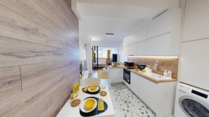 Een moderne keuken met een eethoek, houten vloeren en een wasmachine.