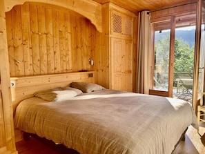 A wooden bedroom with a bed, a window, and a view of the outdoors. - Chalet, terrace, fireplace or stove, parking, 145m², Les Gets (Les Gets)