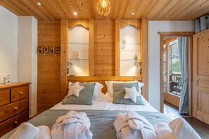 Ein Schlafzimmer mit Holzwänden, einem Bett, zwei Kissen, einem Nachttisch und einer Kommode.