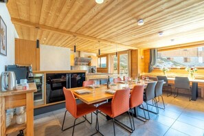 Eine moderne Küche mit Essbereich, Holzboden und großen Fenstern.