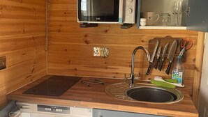 Cocina compacta equipada con microondas, pileta y juego de cuchillos.