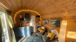 Interior acogedor de una cabaña con kitchenette, una cama y un tapete estampado, además de un cuadro en la pared.