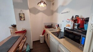 Cocina compacta con lavabo, lavavajillas y un pequeño cubo de basura.