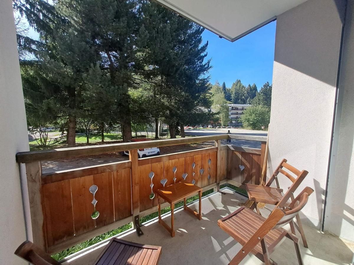 Un balcon avec une balustrade en bois, un banc et deux chaises en bois.